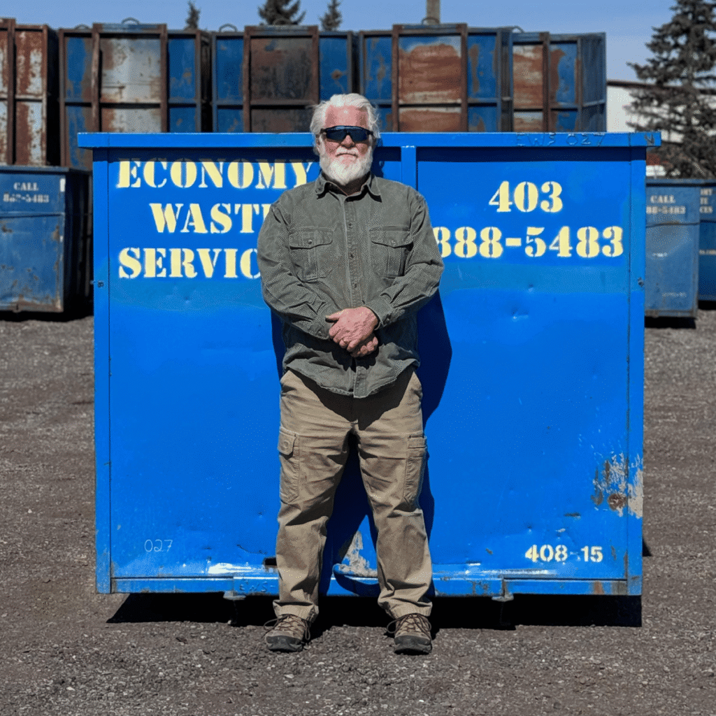 Economy Waste Services Calgary Owner Darrell Standing in Front of a Blue Dumpster